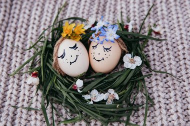 egg with a bow on a textile pink background with white dried flowers and white blooms