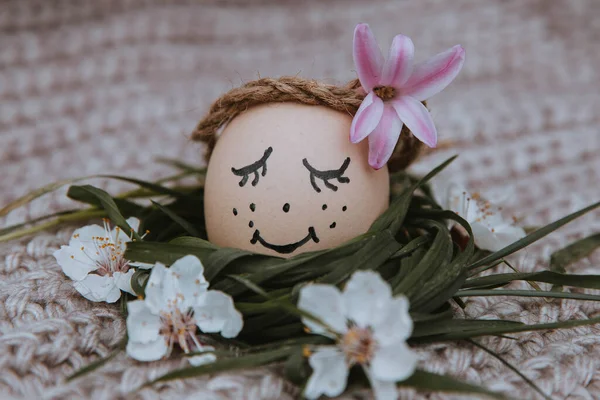 egg with a bow on a textile pink background with white dried flowers and white blooms