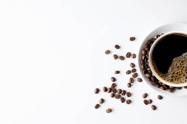 Beyaz masa arkasında bir fincan kahve ve fasulye. en üstteki görünüm