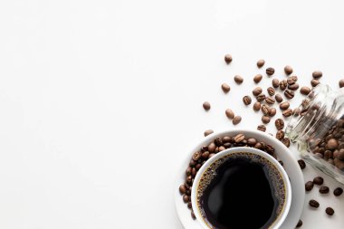 Beyaz masa arkasında bir fincan kahve ve fasulye. en üstteki görünüm