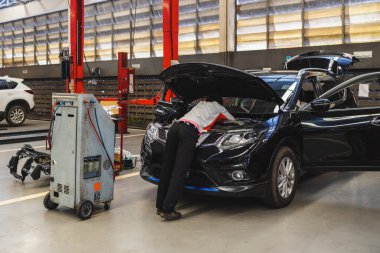 Garaj servis istasyonunda araba tamiri. Arka planda hafif odaklı ve ışığın üstünde.