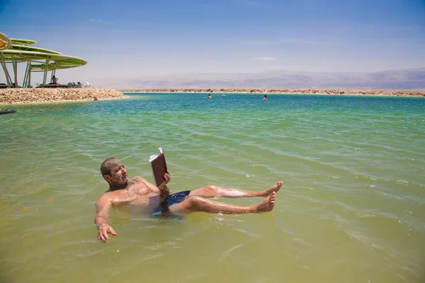 Mann schwimmt und liest ein Buch lizenzfreie Stockfotos