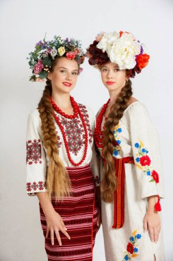 Two Beautiful Ukrainian girls in national costumes vyshyvanka. Studio shoot on white background. Vse bude Ukraine. We're together