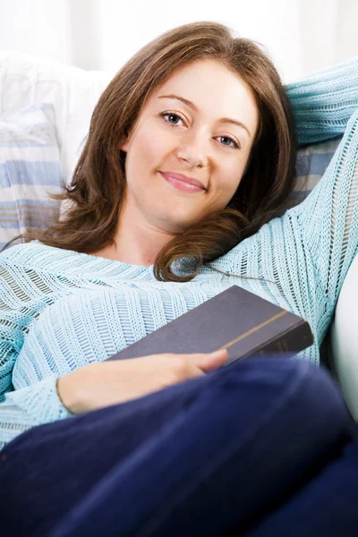 Красивая девушка лежит на диване с книгой — стоковое фото