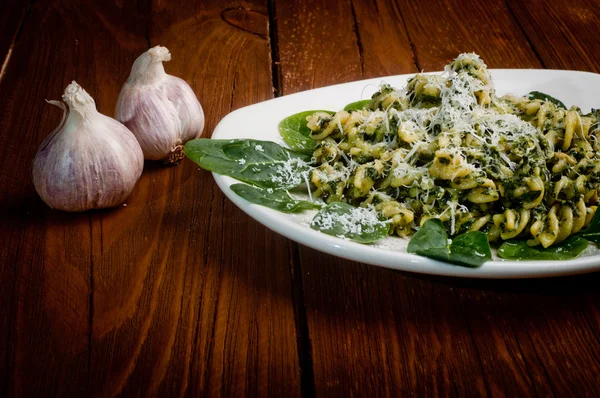 Pasta con espinacas sobre una mesa de madera — Foto de Stock