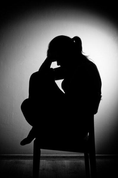 грустная женщина сидит одна в пустой комнате - черно-белая

