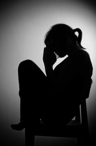 Mujer triste sentada sola en una habitación vacía - blanco y negro —  Fotos de Stock