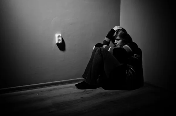 Sad woman sitting alone in a empty room - black and white — Stock Photo, Image