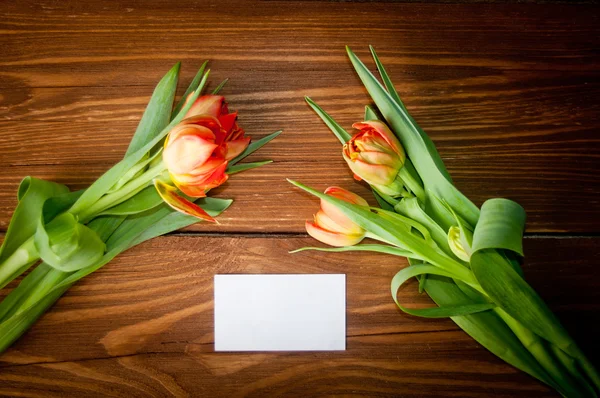 Tulips and blank card on old wooden boards — Stock Photo, Image