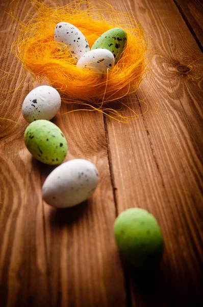 Easter eggs in nest on rustic wooden planks — Stock Photo, Image