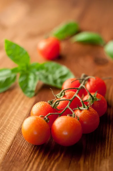 Fresh, ripe cherry tomatoes on an old chopping board. Basil leav — Stock Photo, Image