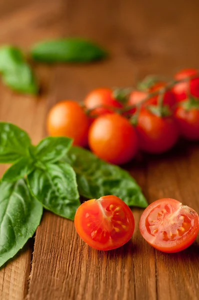 Fresh, ripe cherry tomatoes on an old chopping board. Basil leav — Stock Photo, Image