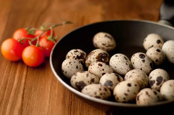 Frying pan with raw quail eggs on wooden boards — Stock Photo, Image