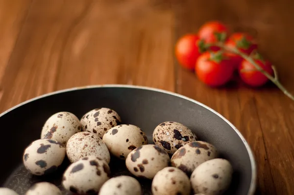 Frying pan with raw quail eggs on wooden boards — Stock Photo, Image