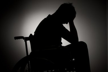 Sad man sitting on wheelchair in empty room
