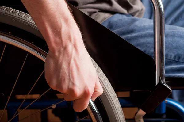 Close-up of male hand on wheel of wheelchair — Stock Photo, Image