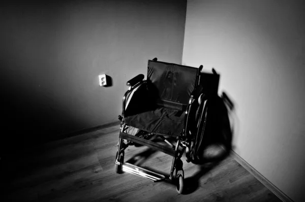 Nahaufnahme leerer Rollstuhl auf dunklem Hintergrund und Schatten in Leer — Stockfoto