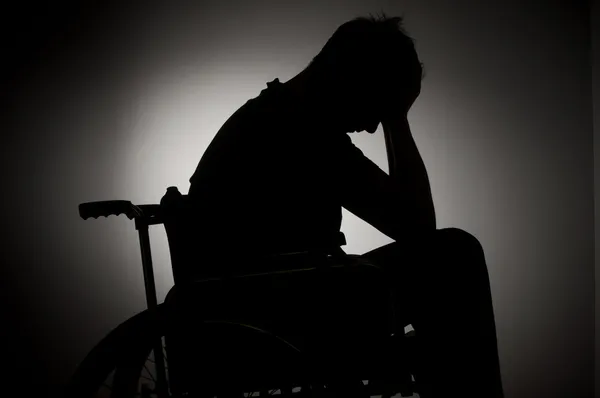 Sad man sitting on wheelchair in empty room — Stock Photo, Image