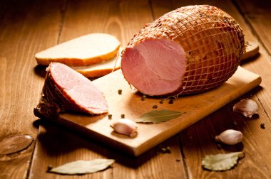 Whole ham with bread in the background, selective focus clipart