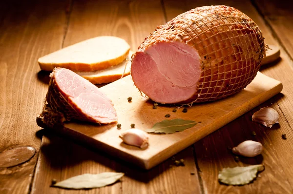 Whole ham with bread in the background, selective focus — Stock Photo, Image