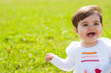 Bebek el ile yukarı bir çim zemin üzerinde gülümseyen