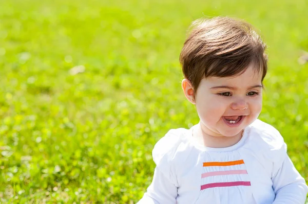 Dulce bebé en un parque sonriendo y mirando hacia otro lado — Foto de Stock