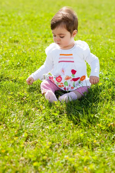 Baby sit on the grass looking at the floor — Stock Photo, Image