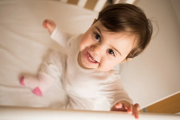 Sorridente bambino sul suo lettino guardando la fotocamera — Foto Stock