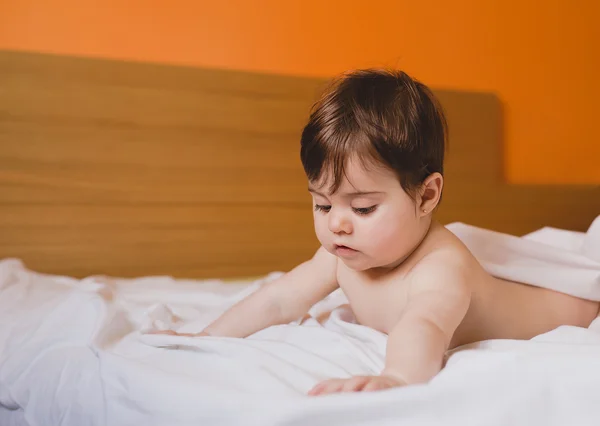 Bebé serio en la cama mirando hacia abajo —  Fotos de Stock