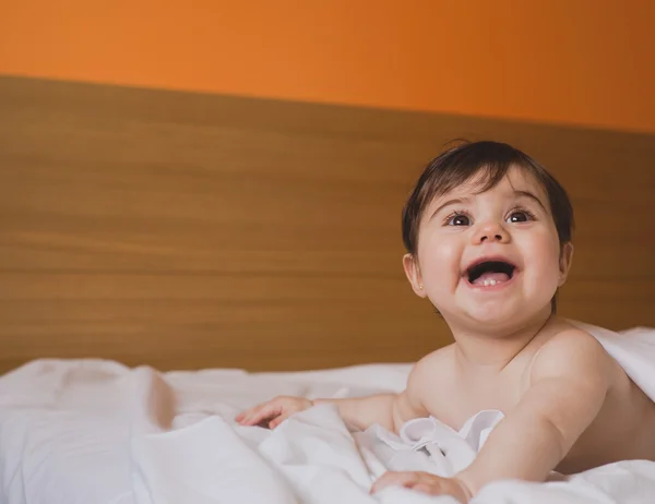 Sorrindo bebê olhando para longe na cama — Fotografia de Stock