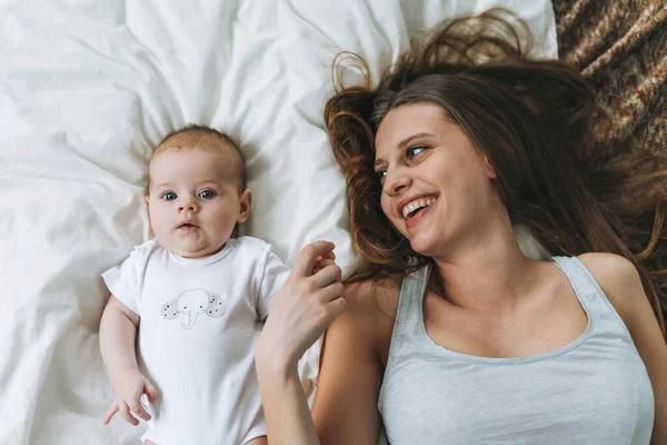 엄마가 귀여운 아기를 침대에서 스러운 톤으로 사랑의 감정을 가지고 즐겁게 — 스톡 사진