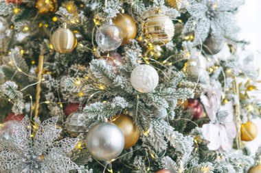 Altın ve beyaz oyuncaklarla süslenmiş Noel ağacı. Işıklar bokeh desenli arka plan.