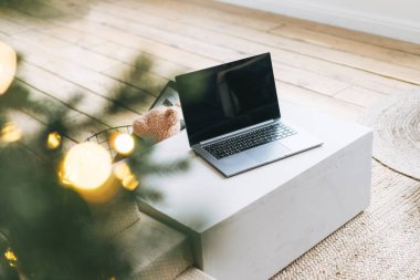 Oturma odasındaki masada açık dizüstü bilgisayar, süslü Noel ağacı, online alışveriş konsepti.