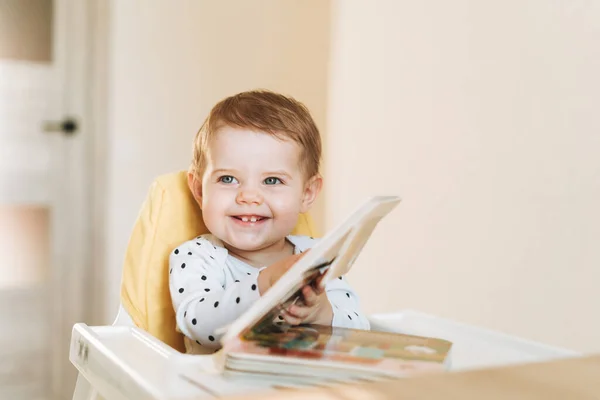 Счастливая Симпатичная Девочка Кресле Бустере Читает Детскую Книгу Дома — стоковое фото