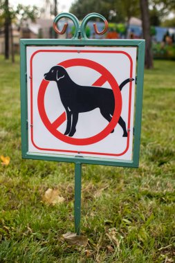 Köpek tabelasına yakın çekim yok. Yeşil çimlerin arka planında sokak işaretçisi. Park çimlerine ve yeşil alanlara dışkılama ve evcil hayvan çalıştırma yasağı. İnsanlar olmadan. Köpekler giremez. Metin için yer