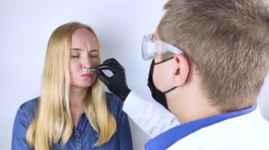 Kız koku kaybı hakkında doktora şikayette bulunuyor. Doktor bir koku testi uygular. Covid-19 teşhisi. Koronavirüsün belirtileri. Karantina ve tecrit. Sars-cov-2 için test
