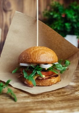 Standart bir hamburgerin yakın çekimi. Restoranda ya da kafede yetişkin fast food 'u. Etli, peynirli ve otlu hamburger malzemelerinin Macro fotoğrafı. Tüm aile için eko-burger.