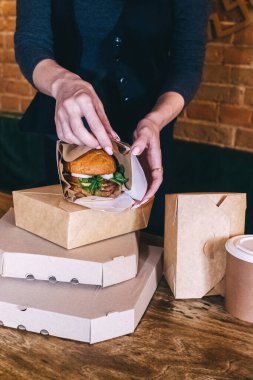Yemek servisi. Kız elinde hazır yiyeceklerle kese kağıdı tutuyor. Covid 19 'a karşı koyma konsepti. Restorandan ya da kafeden teslimat var. Yemek konteynerleri açılıyor