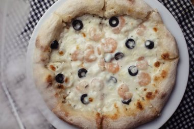 Karidesli pizza yakın plan. Deniz ürünleri ve vejetaryen yemekleri. Restoranlarda ve kafelerde İtalyan yemekleri. Yemek hazırlarken deniz malzemeleri konsepti.