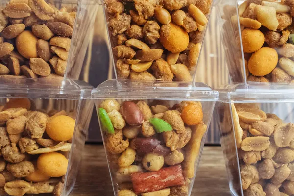 Close-up of a beer snack. Hazelnuts, cashews and peanuts with different flavors in transparent packaging. Snacks go with alcohol. Takeaway food. Concept