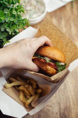 Standart burger ve patates kızartmasının yakın çekimi. Restoranda ya da kafede yetişkin fast food 'u. Etli, peynirli ve otlu hamburger malzemelerinin Macro fotoğrafı. Tüm aile için eko-burger.