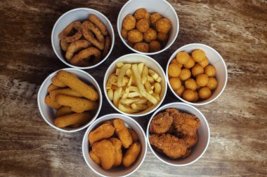 Soğan halkaları, peynir topları, tavuk nuggetları, hamurda kanatlar, patates kızartmaları ve peynir çubukları. Kağıt kovalarda altı tabak. Fast food kafeler ve restoranlar. Yiyecek çiçek şeklinde serilmiştir.