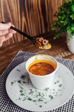 Tek kullanımlık kağıt bardaktaki bir balyozun yakın çekimi. Geleneksel yemek ve yabancı mutfak kavramı. Güvenli çevre dostu tek kullanımlık sofra takımı.