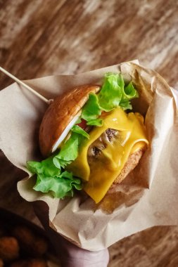 Duble burgerin yakın çekimi. Restoranda ya da kafede yetişkin fast food 'u. Etli, peynirli ve otlu hamburger malzemelerinin Macro fotoğrafı. Tüm aile için eko-burger.