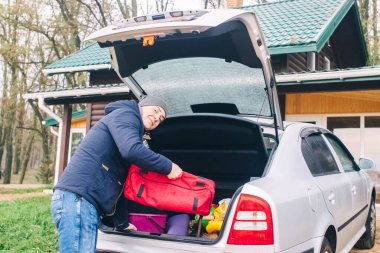 Ormandaki bir kır evine gelen bir adamın yakın çekimi. Ailenin reisi arabanın bagajından çantaları alıyor. Villada zengin bir tatil kavramı.