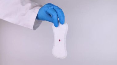 Hipomenoroz. Kadın üzerinde küçük bir damla kan olan jinekolojik bir ped gösteriyor. Regl döneminde küçük miktarlarda ilaç kullanımı. Ağrı ve garip bir döngü şikayetleri var. Jinekolojide hastalıklar