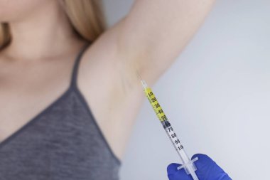 Klinikte hiperhidrozun tedavisi için koltukaltına botulinyum toksin enjekte edilen bir kadın. Artan terleme, anhidroz ya da arızalı bezlerle ilgili sorunların tedavisi. Kozmetoloji