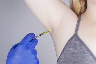 Klinikte hiperhidrozun tedavisi için koltukaltına botulinyum toksin enjekte edilen bir kadın. Artan terleme, anhidroz ya da arızalı bezlerle ilgili sorunların tedavisi. Kozmetoloji