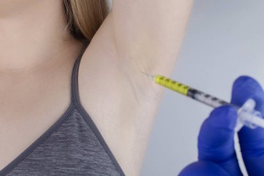 Klinikte hiperhidrozun tedavisi için koltukaltına botulinyum toksin enjekte edilen bir kadın. Artan terleme, anhidroz ya da arızalı bezlerle ilgili sorunların tedavisi. Kozmetoloji