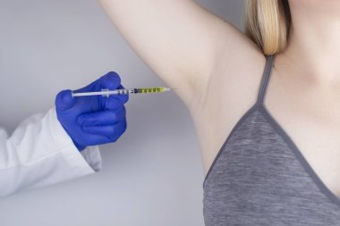 Klinikte hiperhidrozun tedavisi için koltukaltına botulinyum toksin enjekte edilen bir kadın. Artan terleme, anhidroz ya da arızalı bezlerle ilgili sorunların tedavisi. Kozmetoloji